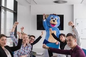 boss dresed as bear having fun with business people in trendy office photo