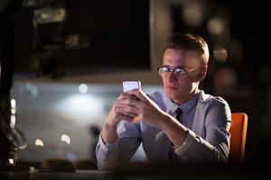 man using mobile phone in dark office photo