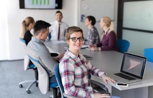portrait of young business woman at office with team on meeting in background photo