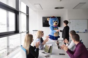 boss dresed as bear having fun with business people in trendy office photo