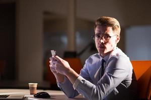 man using mobile phone in dark office photo