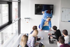 boss dresed as bear having fun with business people in trendy office photo