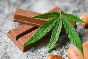 comida de cannabis con hierba de marihuana de hoja de cannabis de chocolate sobre fondo oscuro, deliciosa galleta de postre dulce con planta de hoja de cáñamo thc cbd hierbas comida snack y medicina foto