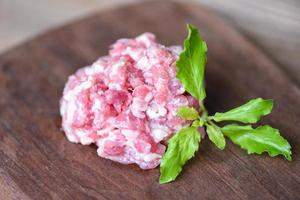 Mincemeat , minced or ground meat - Raw pork with basil leaf on wooden cutting board , Ground Pork photo