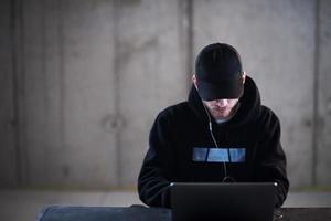 talented hacker using laptop computer while working in dark office photo