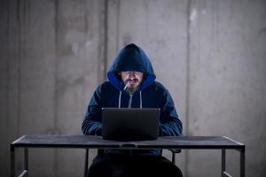 young hacker using laptop computer while working in dark office photo