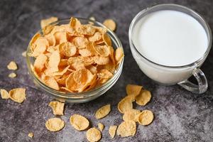 cornflakes bowl breakfast food and snack for healthy food concept, morning breakfast fresh whole grain cereal, cornflakes with milk on dark background photo