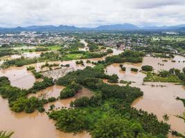 Aerial view river flood village countryside Asia and forest tree, Top view river with water flood from above, Raging river running down jungles lake flowing wild water after the rain photo