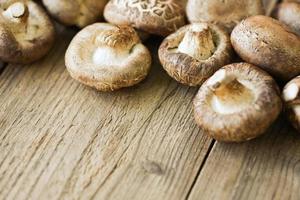 champiñones frescos sobre fondo de mesa de madera - champiñones shiitake foto