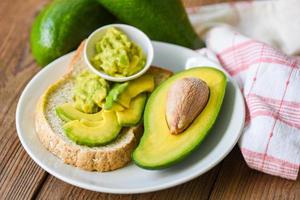 Avocado sliced half and avocado dip mashed on white plate background fruits healthy food concept - avocado toast photo