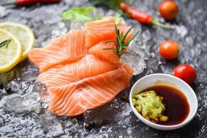 Wasabi sauce raw salmon filet on ice herbs and spices on dark background Fresh salmon fish for cooking salad seafood pepper rosemary lemon pepper japanese food photo