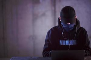 talented hacker using laptop computer while working in dark office photo