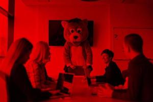 boss dresed as bear having fun with business people in trendy office photo