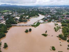 Aerial view river flood village countryside Asia and forest tree, Top view river with water flood from above, Raging river running down jungles lake flowing wild water after the rain photo