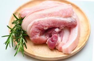 pork on wooden plate with rosemary, fresh raw streaky pork meat for cooking food photo