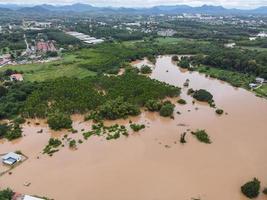 Aerial view river flood village countryside Asia and forest tree, Top view river with water flood from above, Raging river running down jungles lake flowing wild water after the rain photo