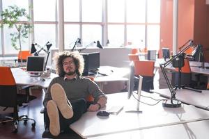 hombre de negocios sentado con las piernas en el escritorio foto