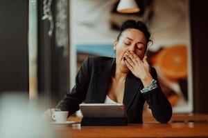 una mujer dormida se sienta en un café durante un descanso y usa una tableta.concepto de negocio. foto