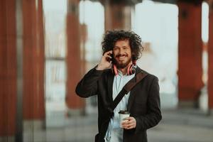 Happy young American holding a coffee. With headphones. Student boy. photo