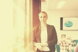 portrait of young business woman at office with team on meeting in background photo