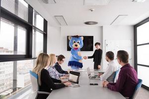 boss dresed as bear having fun with business people in trendy office photo