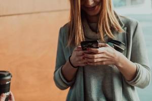 macro photo of a girl drinking coffee and using a cell phone during a break from work.