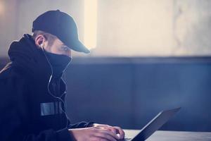 talented hacker using laptop computer while working in dark office photo