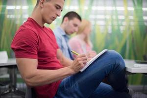 male student taking notes in classroom photo