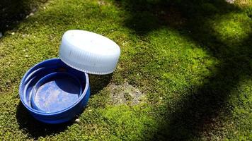 two bottle caps on a green umut surface in the morning photo