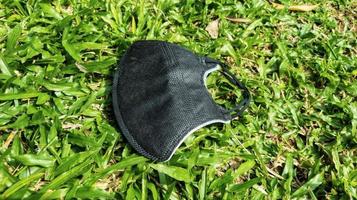 black mouth mask lying on green rumout, green grass background photo