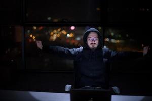 hacker usando una computadora portátil mientras trabaja en una oficina oscura foto