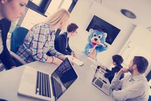 boss dresed as bear having fun with business people in trendy office photo