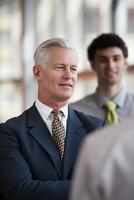 portrait of senior businessman as leader  with staff in background photo