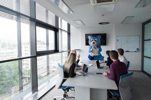 boss dresed as bear having fun with business people in trendy office photo