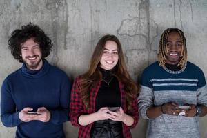 casual multiethnic business team using mobile phones in front of a concrete wall photo