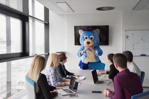 jefe vestido como oso divirtiéndose con gente de negocios en una oficina de moda foto