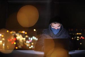 hacker using laptop computer while working in dark office photo