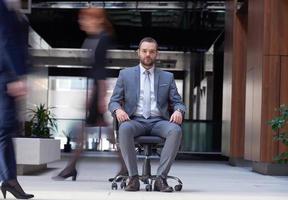 business man sitting in office chair, people group  passing by photo