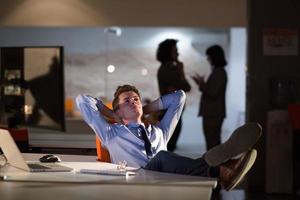 businessman sitting with legs on desk at office photo