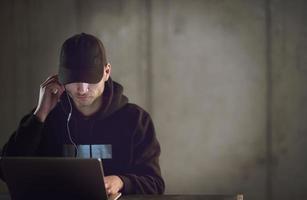 talented hacker using laptop computer while working in dark office photo