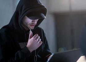 talented hacker using laptop computer while working in dark office photo