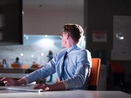 man working on computer in dark office photo