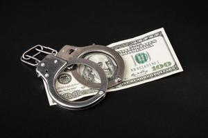 fraud and money laundering, 100 dollars and handcuffs on dark background photo