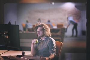 hombre trabajando en una computadora en una oficina oscura foto