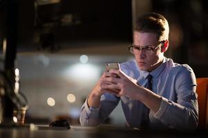 man using mobile phone in dark office photo