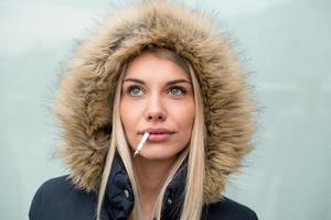 portrait of young blonde girl with cigarette in the mouth photo