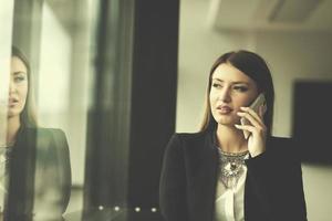 chica de negocios parada en un edificio moderno cerca de la ventana con teléfono foto