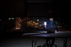 hacker using laptop computer while working in dark office photo