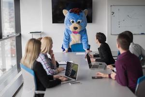 boss dresed as bear having fun with business people in trendy office photo