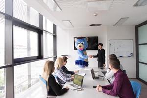 boss dresed as bear having fun with business people in trendy office photo